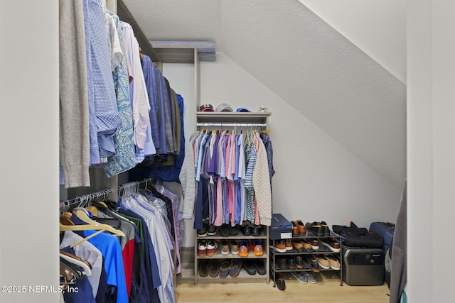 walk in closet with wood-type flooring and vaulted ceiling