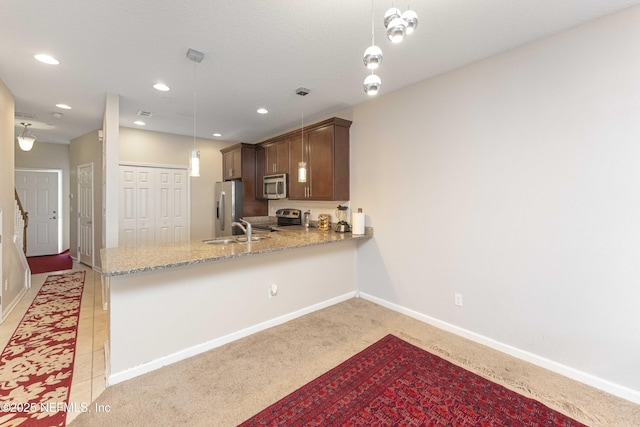 kitchen with kitchen peninsula, pendant lighting, appliances with stainless steel finishes, sink, and light colored carpet