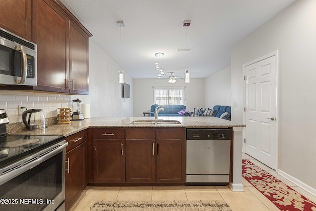 kitchen with sink, pendant lighting, kitchen peninsula, and stainless steel appliances