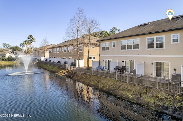 rear view of house featuring central air condition unit and a water view