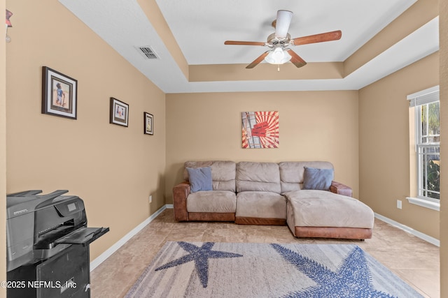 living room with a tray ceiling and ceiling fan