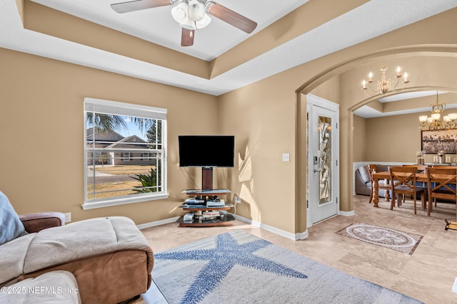 sitting room with a raised ceiling and ceiling fan with notable chandelier