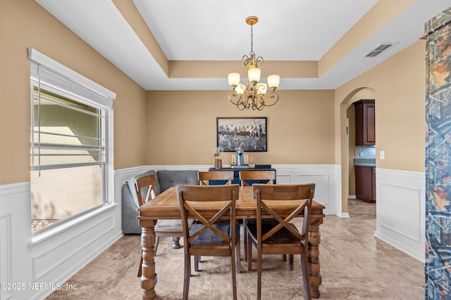 dining space with a raised ceiling and a notable chandelier