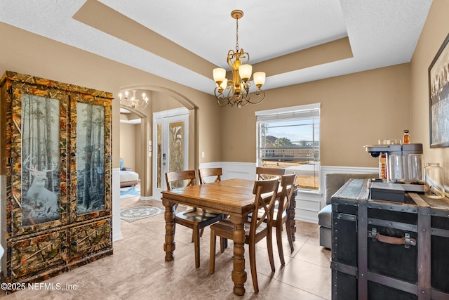 dining area featuring a notable chandelier, light tile patterned floors, a raised ceiling, and a textured ceiling