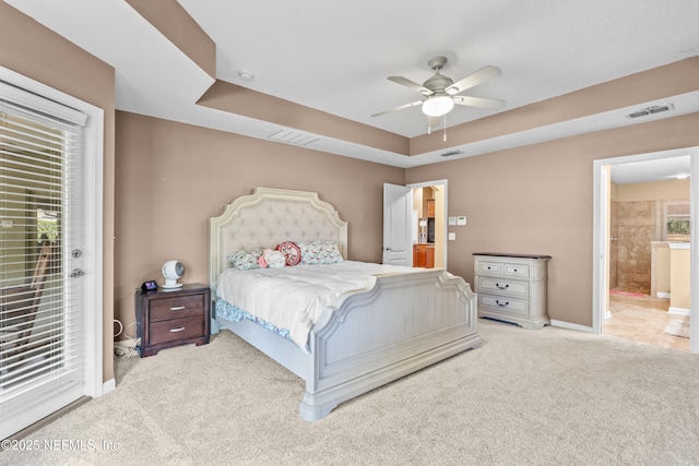 carpeted bedroom with a tray ceiling, access to outside, ceiling fan, and ensuite bathroom