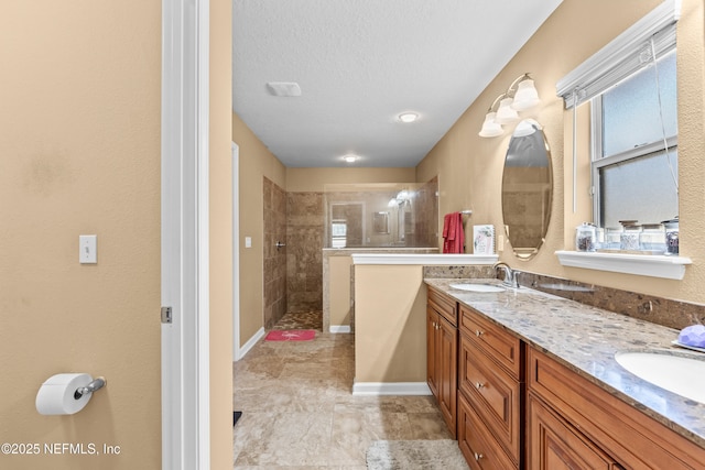 bathroom with vanity, a textured ceiling, and a tile shower