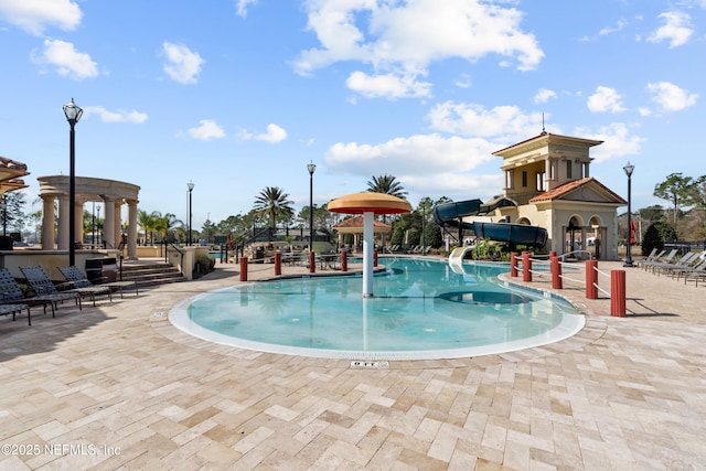 view of swimming pool featuring a water slide and a patio area