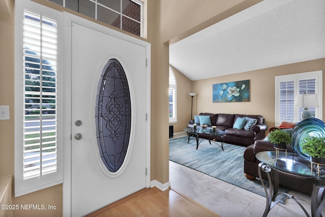 entryway featuring lofted ceiling, light hardwood / wood-style flooring, and a textured ceiling