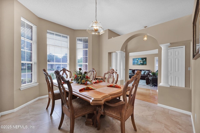 dining room with ornate columns, light tile patterned floors, and a textured ceiling