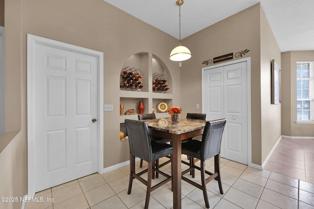 tiled dining space featuring built in features and a textured ceiling