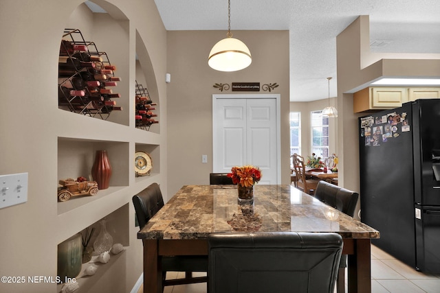 tiled dining room featuring built in shelves and a textured ceiling