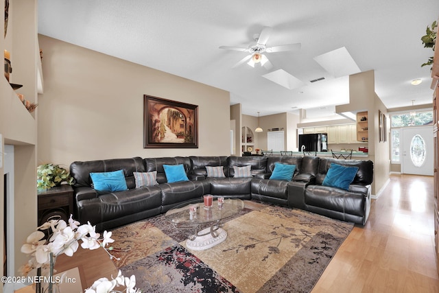 living room with light hardwood / wood-style floors and a skylight