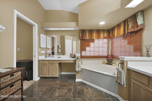 bathroom with vanity, a tub, and lofted ceiling