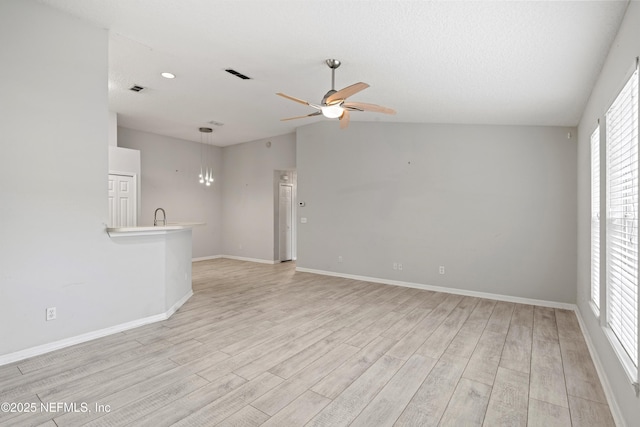 unfurnished living room featuring lofted ceiling, sink, ceiling fan, light hardwood / wood-style floors, and a textured ceiling