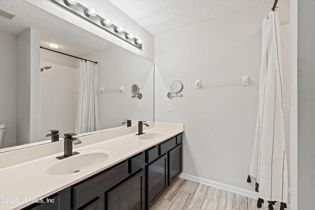 bathroom featuring vanity, toilet, a textured ceiling, and walk in shower