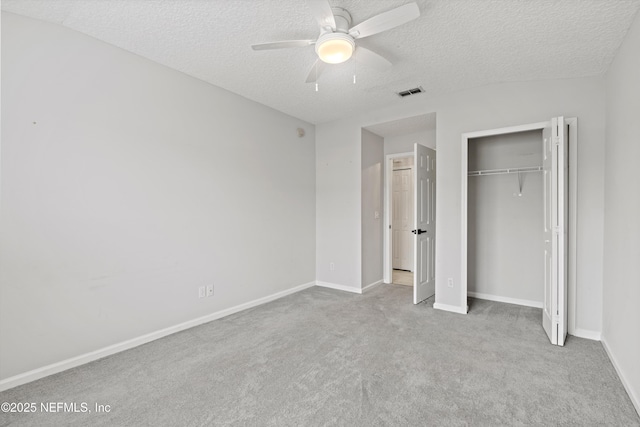 unfurnished bedroom with light colored carpet, a textured ceiling, ceiling fan, and a closet