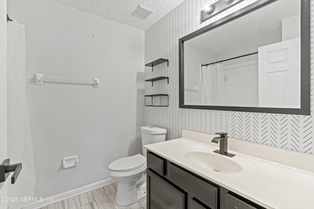 bathroom with vanity, curtained shower, a textured ceiling, and toilet