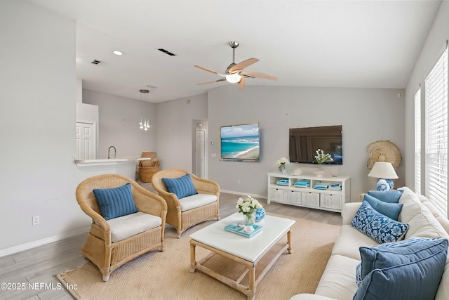 living room with ceiling fan, vaulted ceiling, and light wood-type flooring