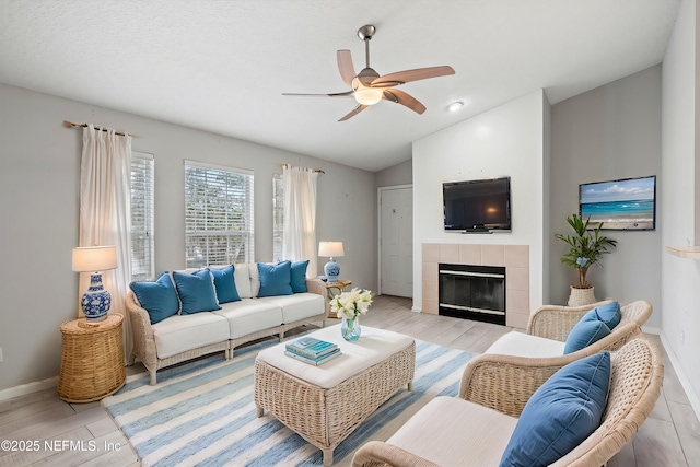 living room featuring a tile fireplace, lofted ceiling, and ceiling fan