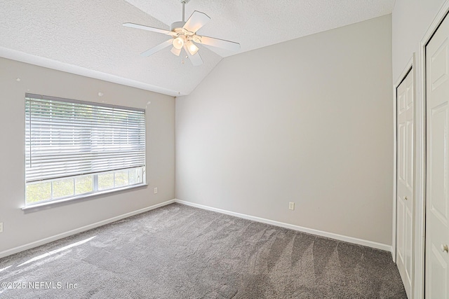 carpeted empty room featuring lofted ceiling, ceiling fan, and a textured ceiling