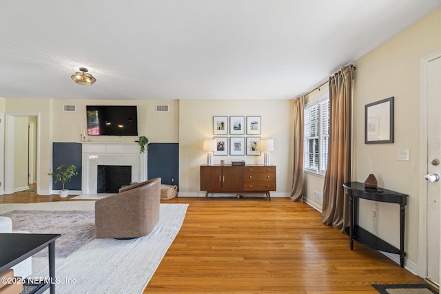 living room featuring a tile fireplace and light wood-type flooring