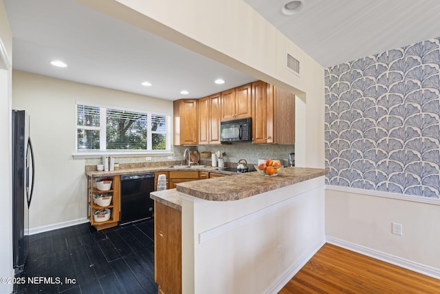 kitchen with dark hardwood / wood-style flooring, sink, black appliances, and kitchen peninsula