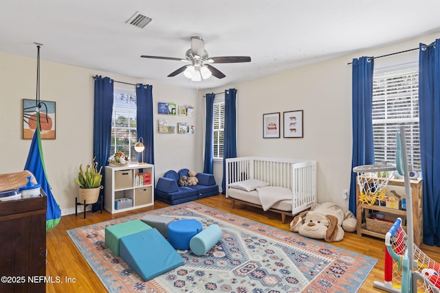 bedroom with multiple windows, wood-type flooring, and ceiling fan