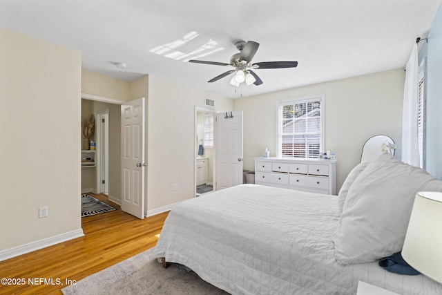 bedroom with hardwood / wood-style flooring, ensuite bath, and ceiling fan