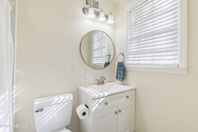 bathroom with vanity, toilet, and a wealth of natural light