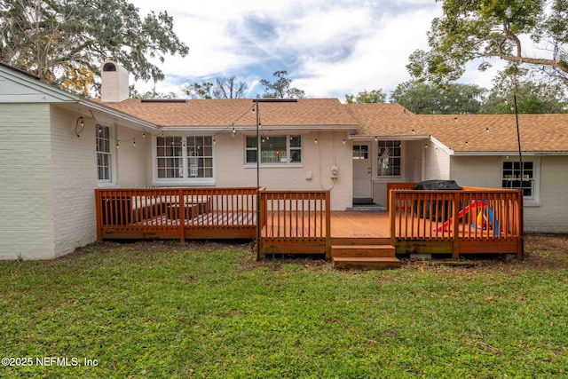 rear view of house featuring a lawn and a deck