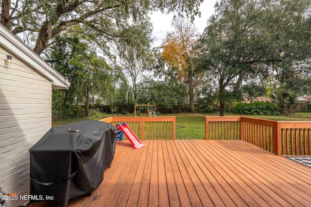 wooden terrace with area for grilling, a yard, and a playground