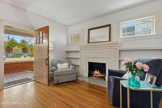 living area with crown molding, hardwood / wood-style flooring, a fireplace, and built in features