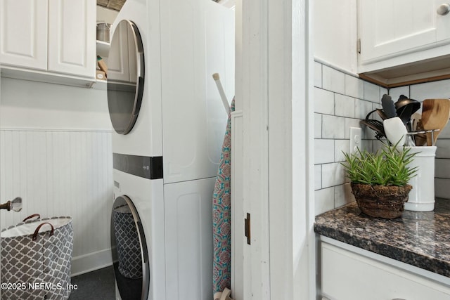 laundry room with stacked washer / dryer and cabinets