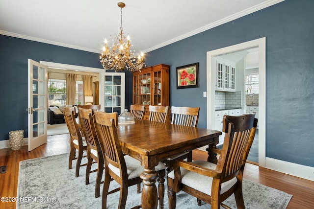 dining room with ornamental molding, hardwood / wood-style floors, and a notable chandelier