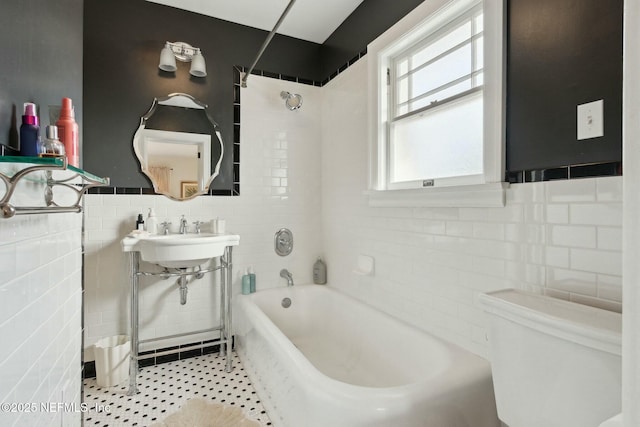 full bathroom featuring tiled shower / bath combo, sink, tile walls, and toilet