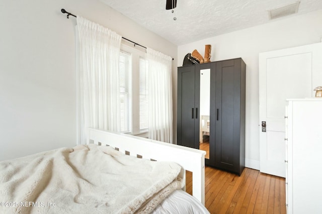 bedroom with ceiling fan, a textured ceiling, and light hardwood / wood-style flooring