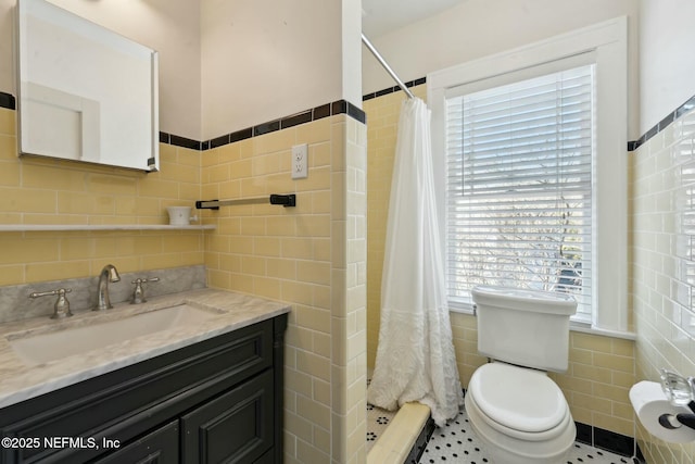 bathroom with toilet, tile walls, vanity, and walk in shower