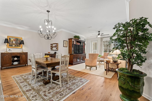 dining area with crown molding, ceiling fan with notable chandelier, and light hardwood / wood-style flooring