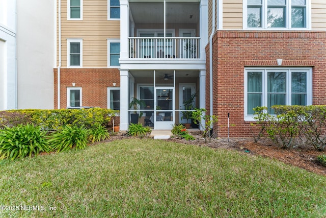 rear view of house featuring a sunroom and a lawn