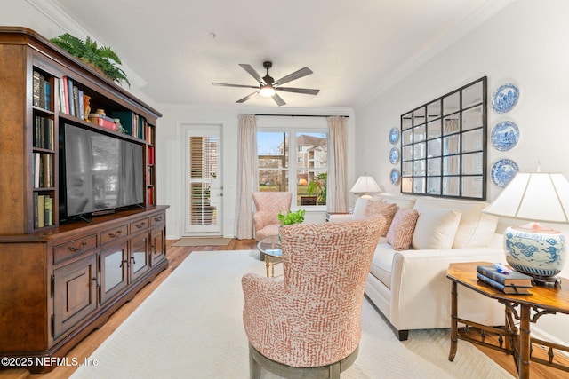 living room with ornamental molding, light hardwood / wood-style floors, and ceiling fan