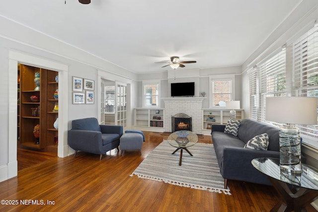 living room featuring ceiling fan, dark hardwood / wood-style floors, and a fireplace