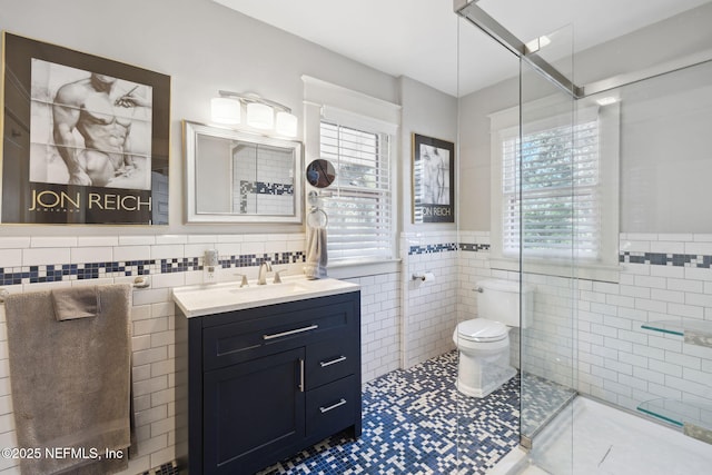 bathroom with tile patterned flooring, vanity, tile walls, toilet, and a shower with shower door