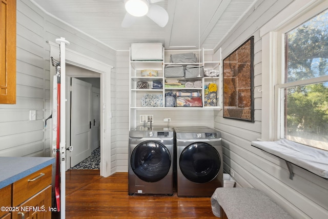 laundry room featuring washer and dryer, dark hardwood / wood-style floors, ceiling fan, and wooden walls