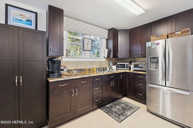 kitchen with dark brown cabinets, sink, light tile patterned floors, light stone counters, and stainless steel appliances