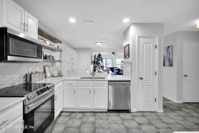 kitchen featuring appliances with stainless steel finishes, a textured ceiling, sink, white cabinets, and backsplash