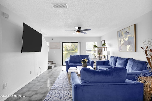 living room with a textured ceiling and ceiling fan