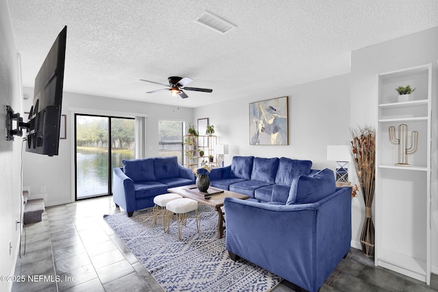 living room featuring ceiling fan, a textured ceiling, built in features, and tile patterned flooring