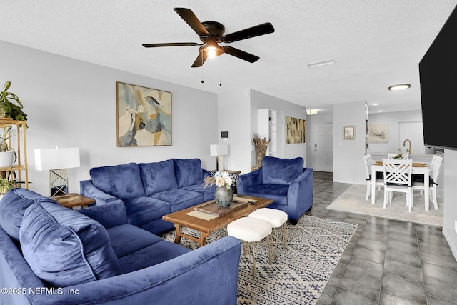 living room with a textured ceiling and ceiling fan