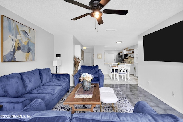 living room with ceiling fan and a textured ceiling