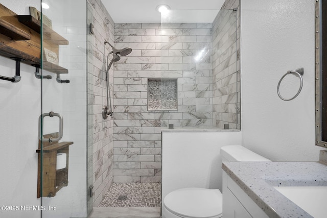 bathroom featuring vanity, a shower with shower door, and toilet